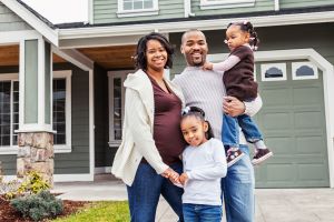 Pregnant family standing outside of a home